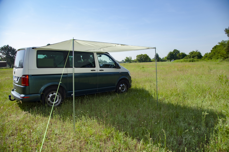 VW Bus mit montiertem Sonnersegel auf Wiese