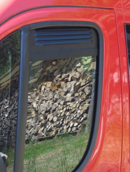 Schwarzes Lüftungsgitter auf getönter Seitenscheibe eines roten Ducato montiert, sorgt für Belüftung im Fahrzeuginneren