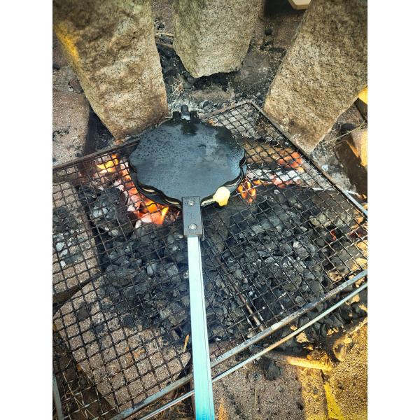 Origin Outdoors Waffeleisen über offenem Feuer, auf einem Grillrost liegend und einsatzbereit positioniert.